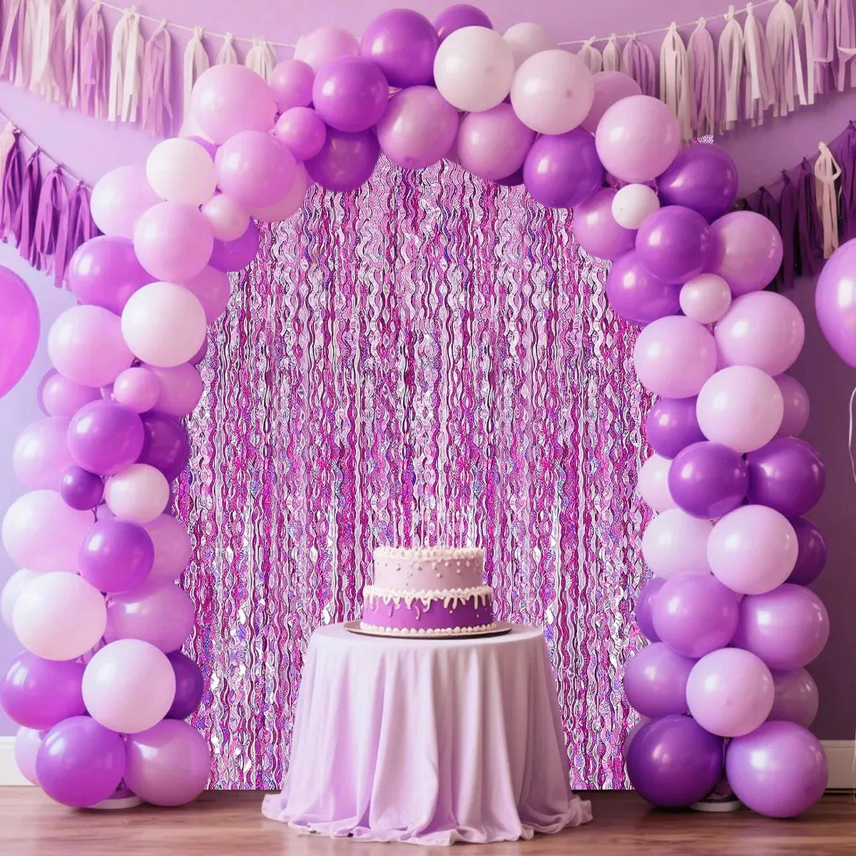 A purple and pink sequin glitter party backdrop featuring balloon arches and a draped curtain.