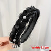 Black braided hair band with pearl accents shown being held by a hand