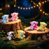 A set of colorful resin bear figurines, including pink, blue, and yellow, displayed on wooden stumps in a forest setting.