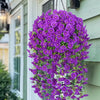 A vibrant purple artificial morning glory hanging vine cascading down a light green siding wall.