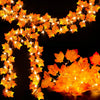 An autumn leaf garland with warm LED lights strung across a dark background for fall decoration.