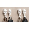 Four white skull wall hooks with leather straps are displayed against a beige background.