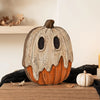 A distressed, orange and white vintage carved pumpkin decor set sitting on a wooden surface.