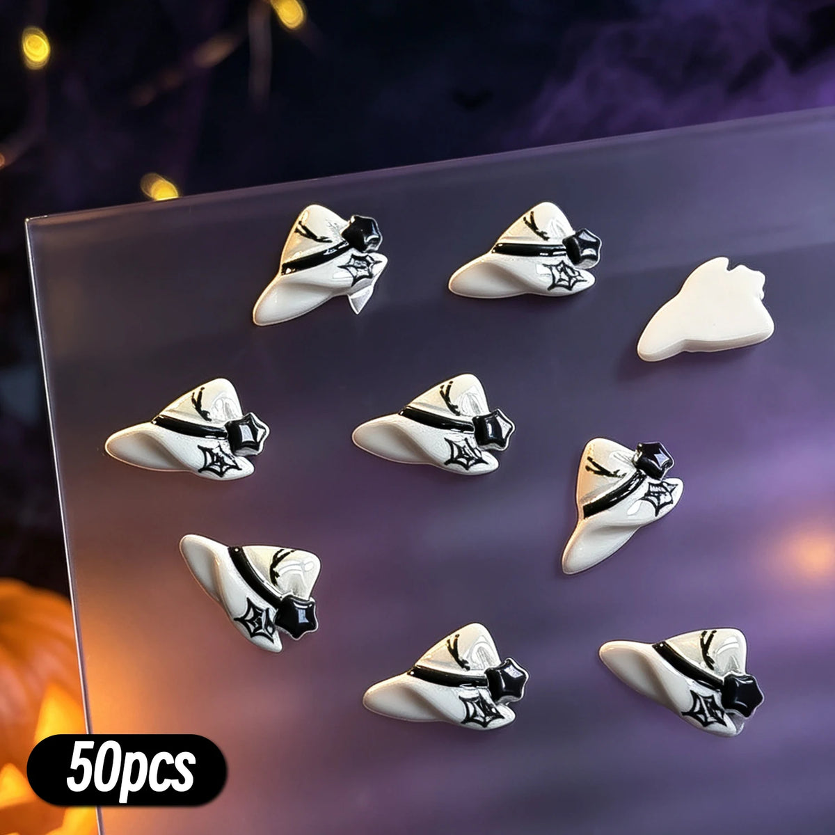 A variety pack of 50 Halloween themed resin nail charms featuring black and white skulls and bats on a clear surface.