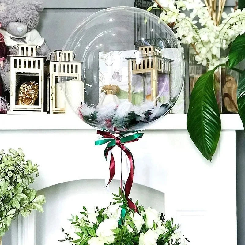 A clear inflatable glass sphere filled with decorative elements and a ribbon, displayed on a white mantelpiece.