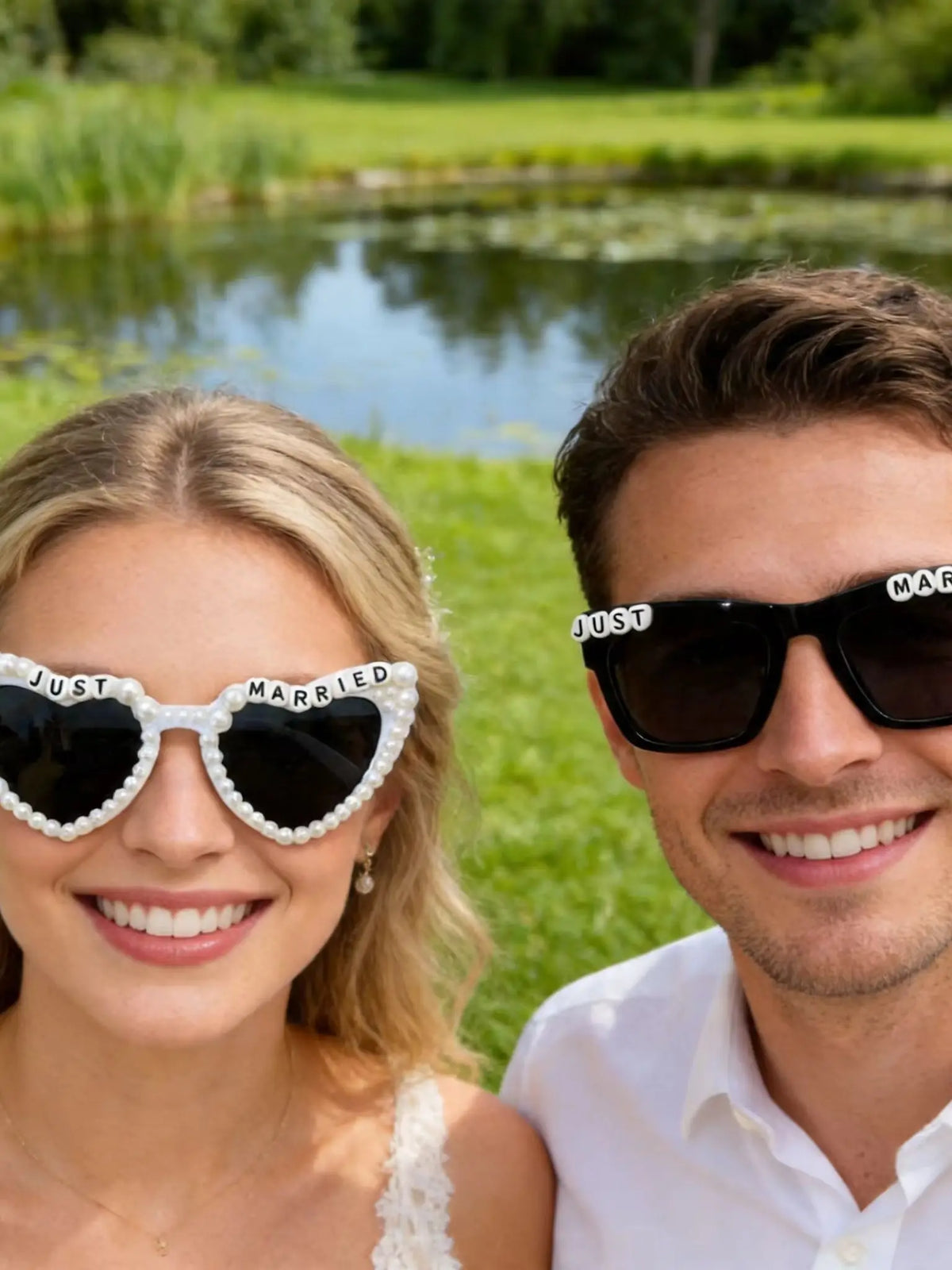 A smiling bride and groom wearing pearl decor glasses for wedding photos outdoors.