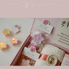 A pink box contains a scented tea light candle and a white fluffy item with a gold beaded decoration.