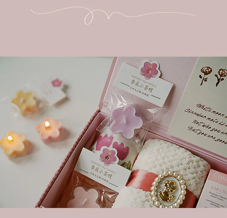 A pink box contains a scented tea light candle and a white fluffy item with a gold beaded decoration.