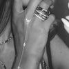 Close-up of a hand wearing multiple ultra-thin layering chain bracelets on the wrist.