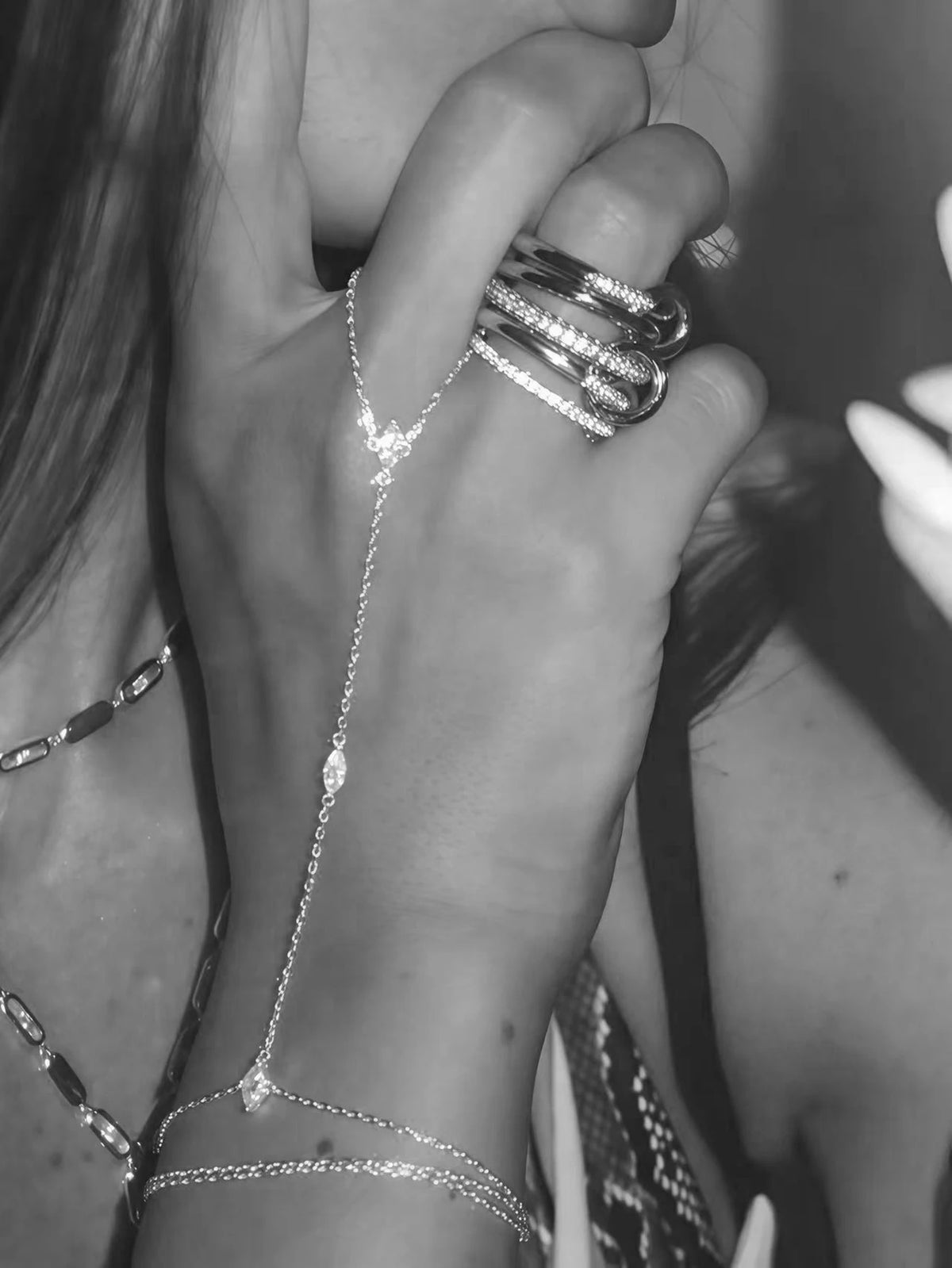 Close-up of a hand wearing multiple ultra-thin layering chain bracelets on the wrist.
