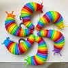 A colorful, flexible, segmented slug toy made of plastic in rainbow colors, shown curled up.