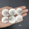 A hand holds several natural rose quartz heart-shaped stones showing swirling patterns and a Shiva eye design.