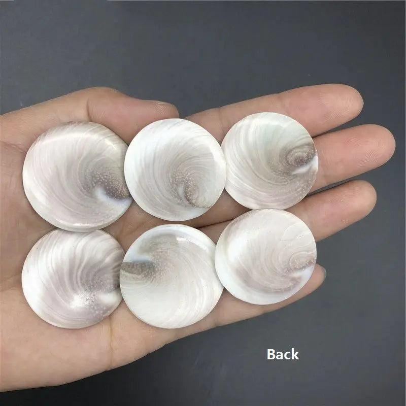 A hand holds several natural rose quartz heart-shaped stones showing swirling patterns and a Shiva eye design.