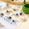 Handcrafted crystal spider figurines with various colors and textures displayed on a light background.