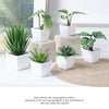 A set of six small artificial green plants in white pots displayed on a light surface with a woven mat.