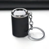 A small black cylindrical coin holder keychain with a silver ring and chain.