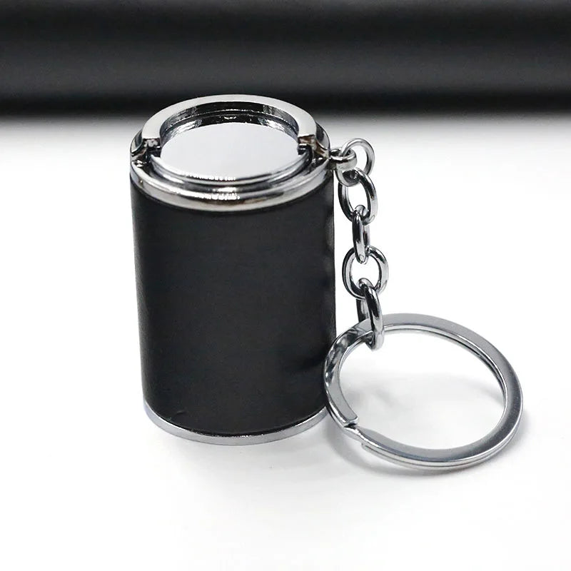 A small black cylindrical coin holder keychain with a silver ring and chain.