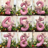 A set of pink 32-inch number balloons shaped like the numbers 1 through 9 with matte bow decor displayed in a floral arrangem
