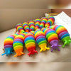 A colorful, flexible 3D articulated fidget slug toy arranged in a rainbow gradient on a light surface.