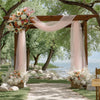 An elegant wooden arbor decorated with pink tulle draping and floral arrangements in a natural outdoor setting.