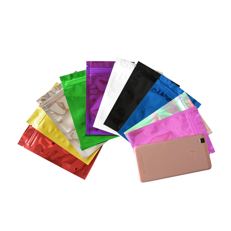 A collection of vibrant foil zip bags in various colors including green, purple, white, black, and blue, displayed on a white