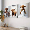 Wall art featuring three paintings of Highland cows, one standing on a toilet.