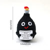 Black crochet potato doll with a red and yellow pompom on top and an inspirational slogan tag.
