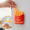 A hand is placing an orange french fry shaped sealing clip into a red container labeled Fries Clips on a white surface.