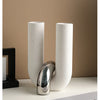 Two tall, cylindrical ceramic vases with a speckled white finish standing on a white surface.