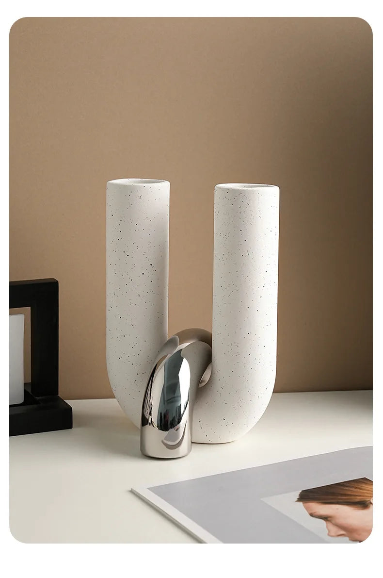 Two tall, cylindrical ceramic vases with a speckled white finish standing on a white surface.