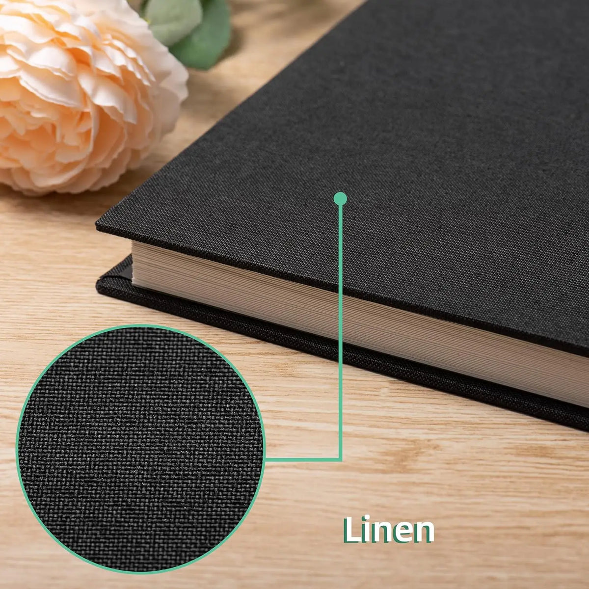 A close-up view of a black magnetic scrapbook album with a linen texture, showing the spine and a detail circle.