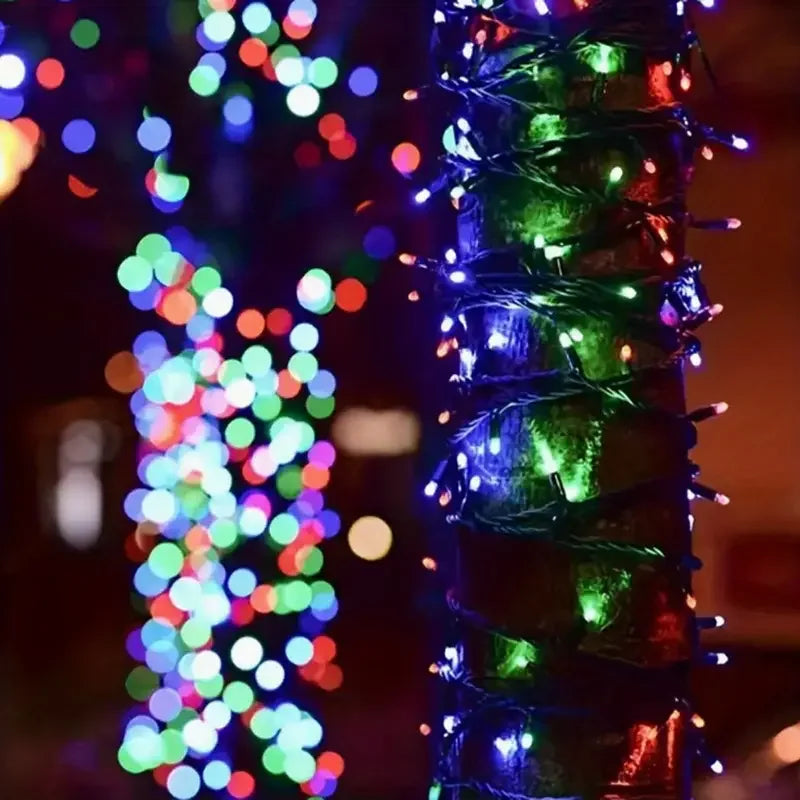 Close-up of bright, multicolored LED string lights wrapped around a green pole in a dark outdoor setting.