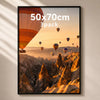 A framed photograph of a sunset landscape featuring numerous hot air balloons over rugged mountains.