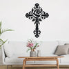 Black metal rose cross wall decor mounted above a light gray sofa.