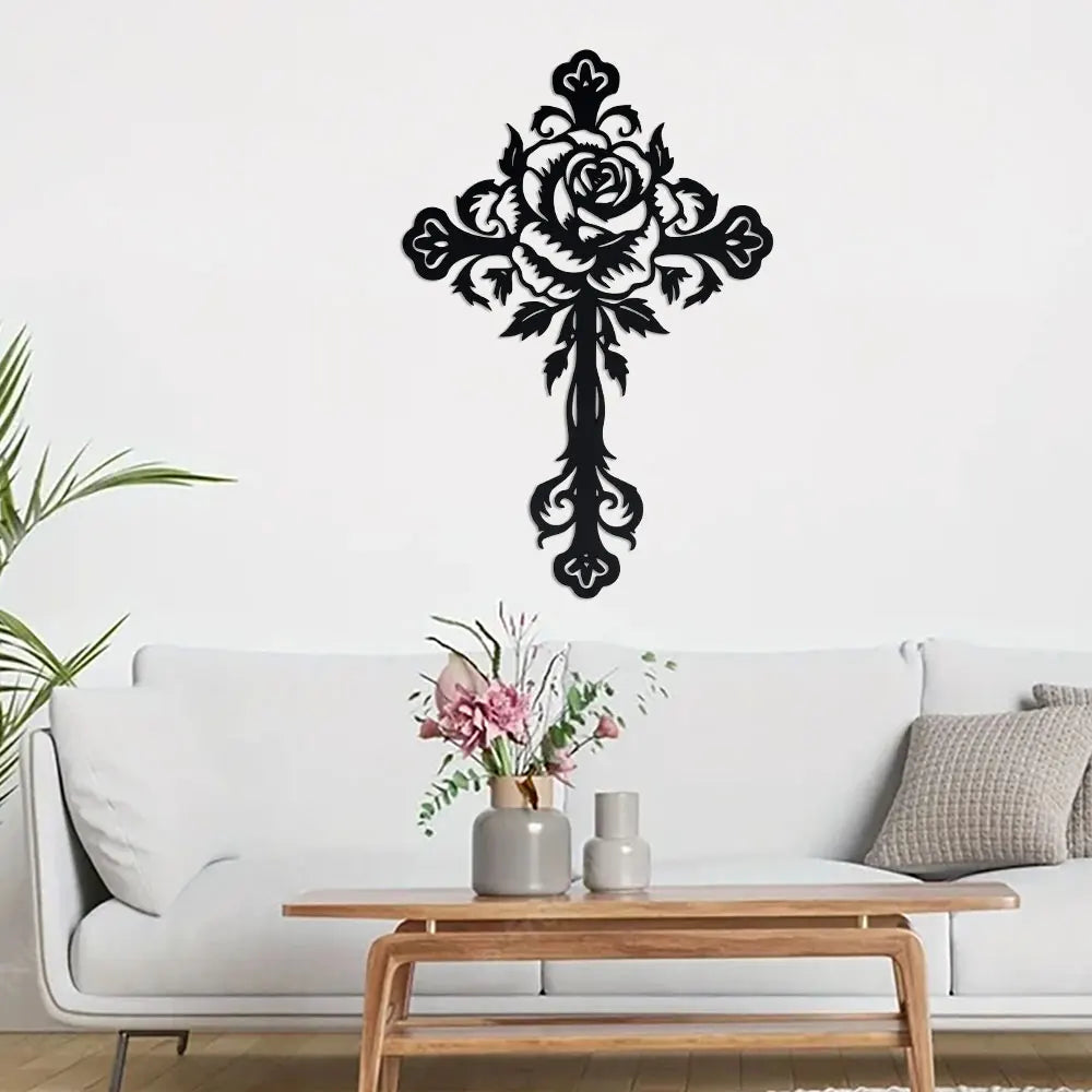 Black decorative metal cross wall art featuring a detailed rose design mounted on a wooden table.