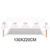 Pink bow disposable party tableware set with birthday decorations displayed on a table.