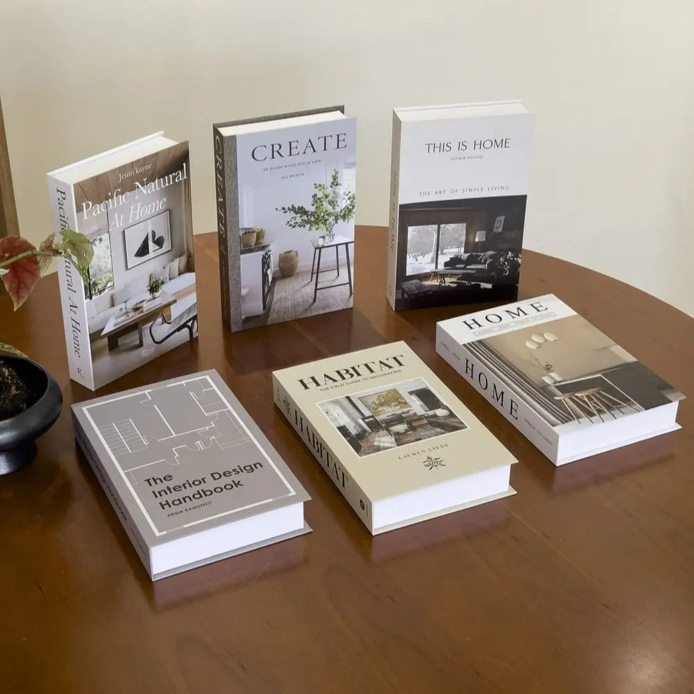 A collection of six hardcover books on home decor and design displayed on a wooden table.