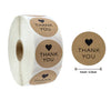 Roll of kraft paper thank you stickers with round labels featuring a heart design