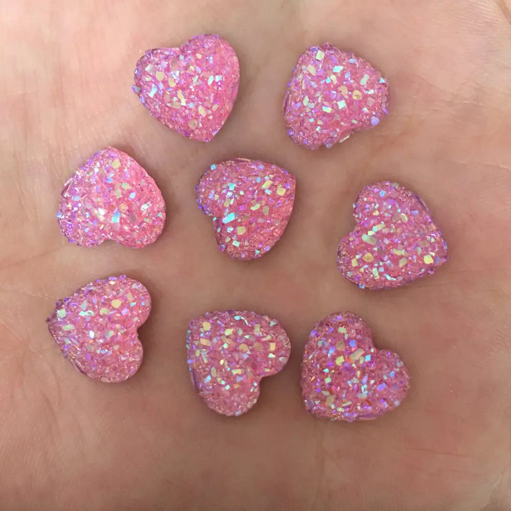 Acht rosa herzförmige Strassornamente verstreut auf einer Hand.