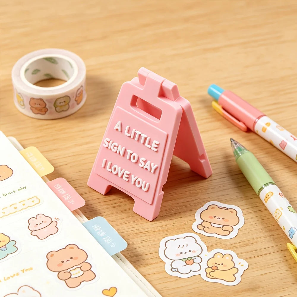 A pink 3D letter sign shaped like a house with the words I love you, next to related crafting supplies.