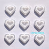 Six heart-shaped acrylic charms in various translucent colors casting shadows on a white surface.