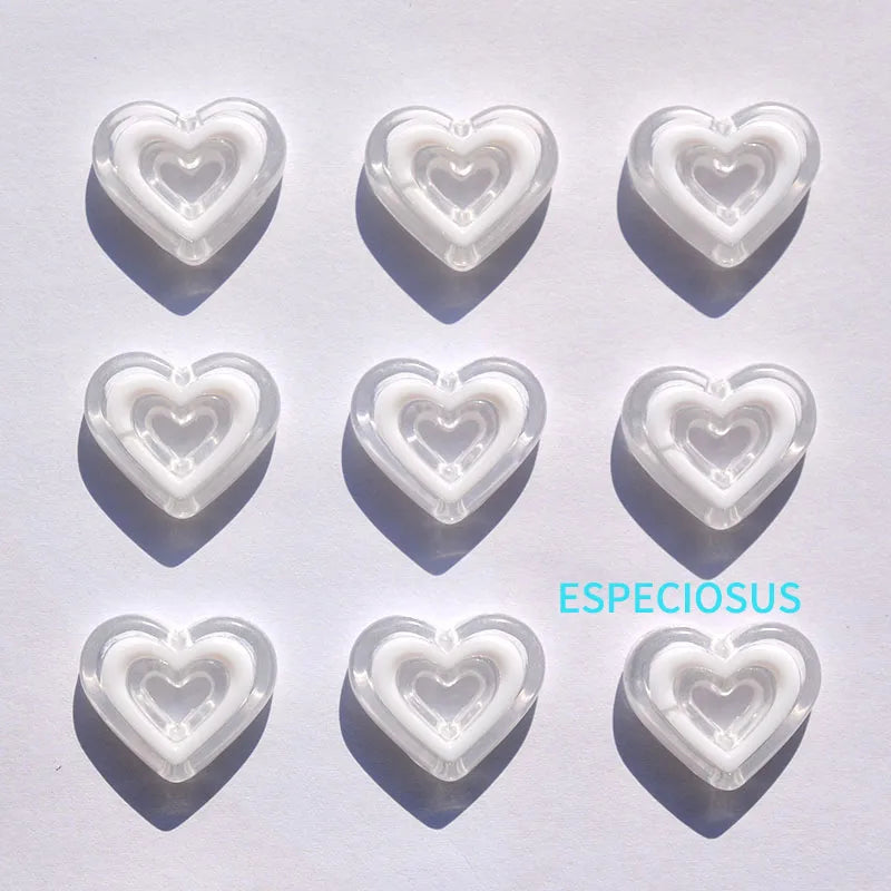 Six heart-shaped acrylic charms in various translucent colors casting shadows on a white surface.