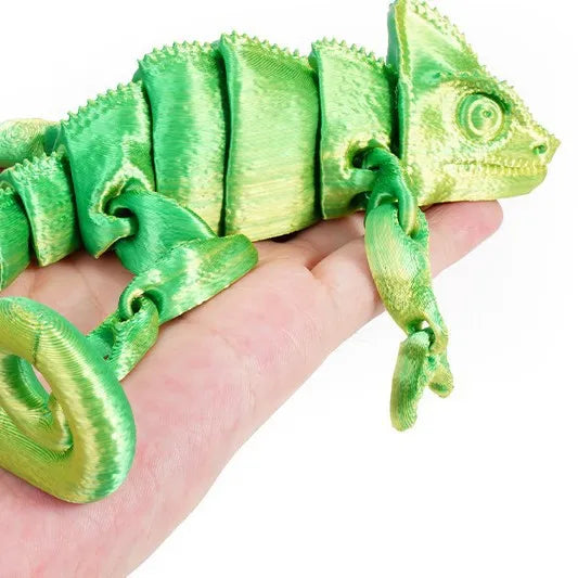 A bright green articulated 3D printed dragon lizard figurine is held in a person's hand.