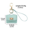 A light mint green mini leather openable bag keychain with a gold-tone clasp and a light blue cord.