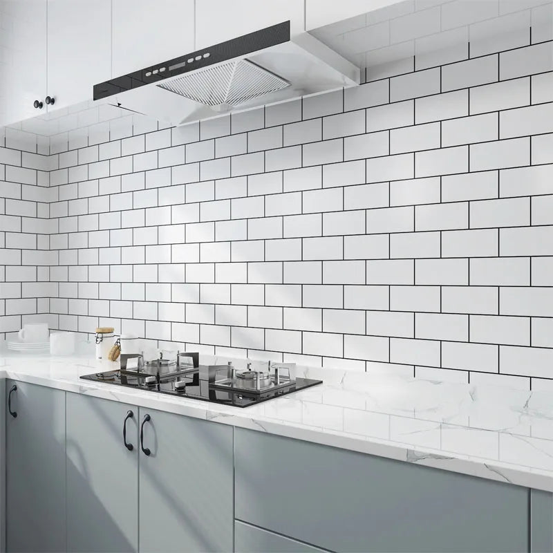 A modern kitchen featuring white subway tile backsplash, gray cabinets, and a stainless steel range hood.