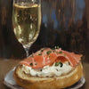 A glass of white wine next to a plate of smoked salmon and cream on toast.