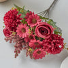 A bouquet of artificial silk flowers in shades of pink and red, including roses and carnations.