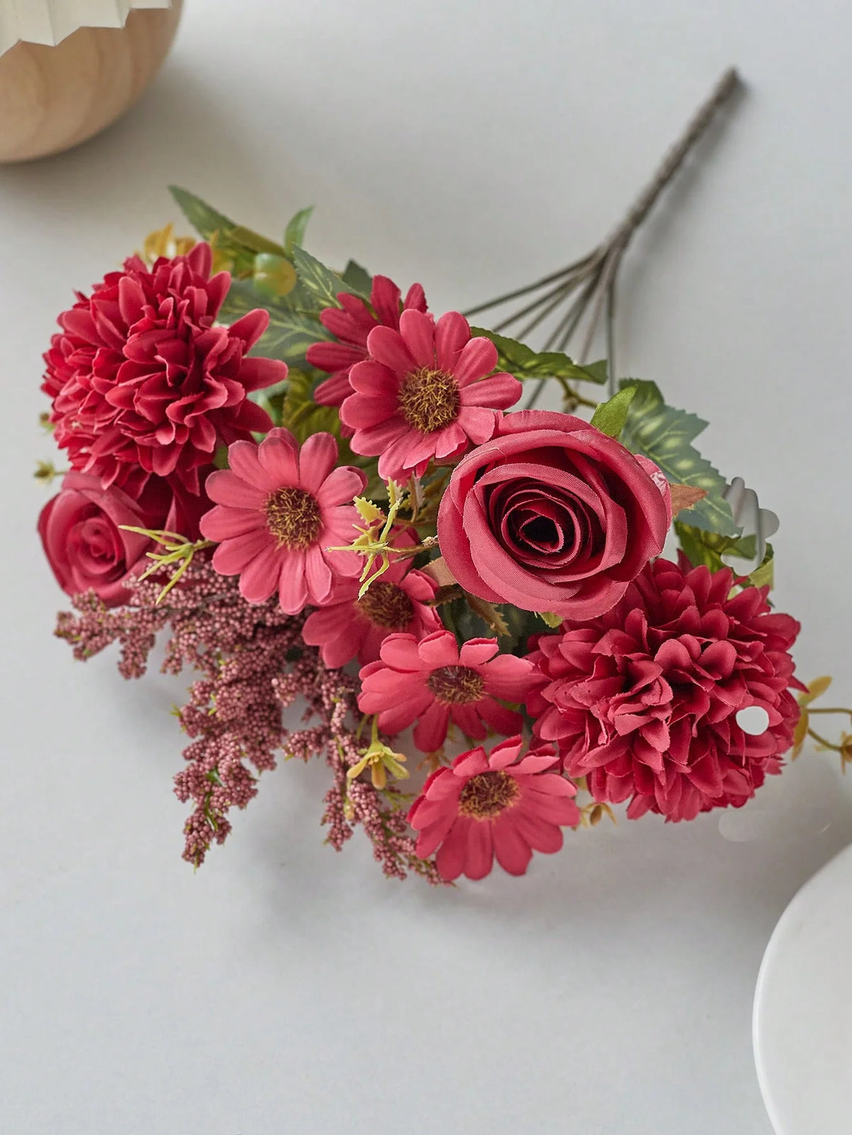 A bouquet of artificial silk flowers in shades of pink and red, including roses and carnations.