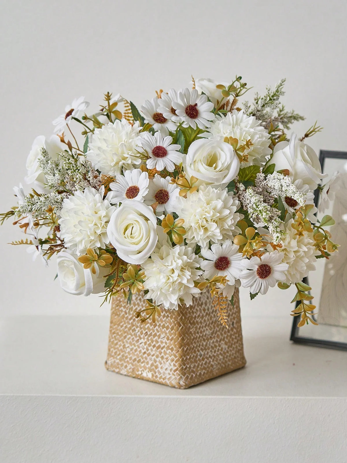 A bouquet of white and cream artificial silk flowers featuring roses, daisies, and filler greenery in a gold textured box.
