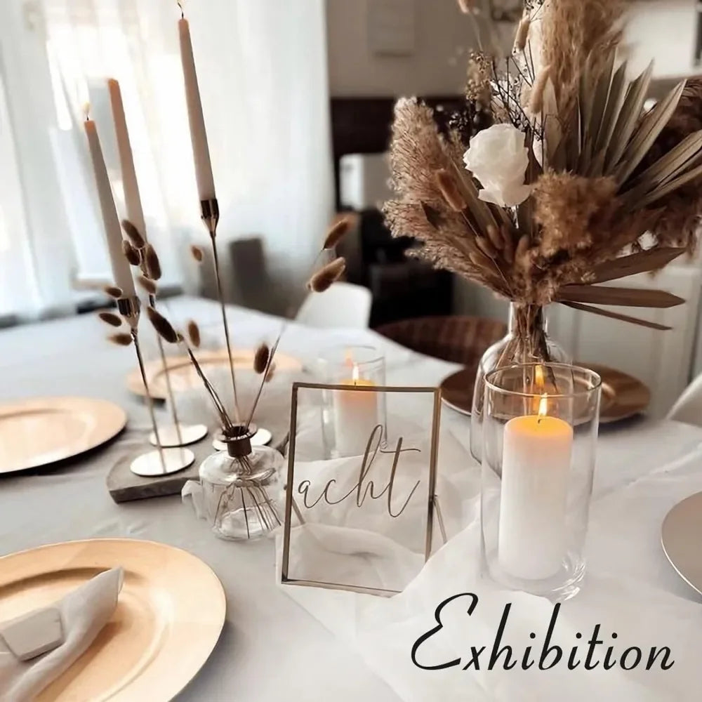 A display of three metal taper candle holders with lit candles on a white tablecloth.